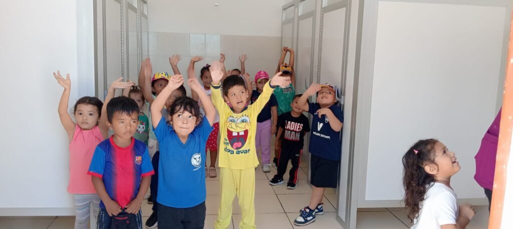 Niños sonrientes con las manos en alto, mostrando su alegría durante una actividad en la iglesia bautista.