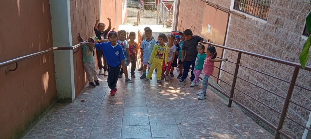 Un grupo de niños bajando por una rampa, jugando y riendo mientras caminan hacia la iglesia bautista.