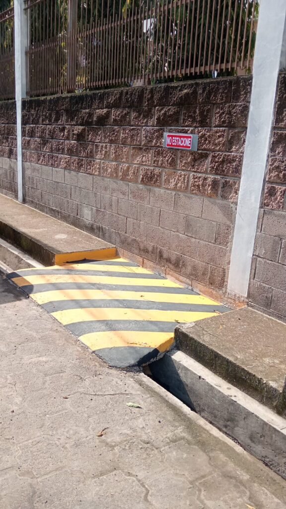Un aviso de "No Estacionar" junto a una acera con marcas amarillas, indicando las normas de estacionamiento cerca en la iglesia bautista.
